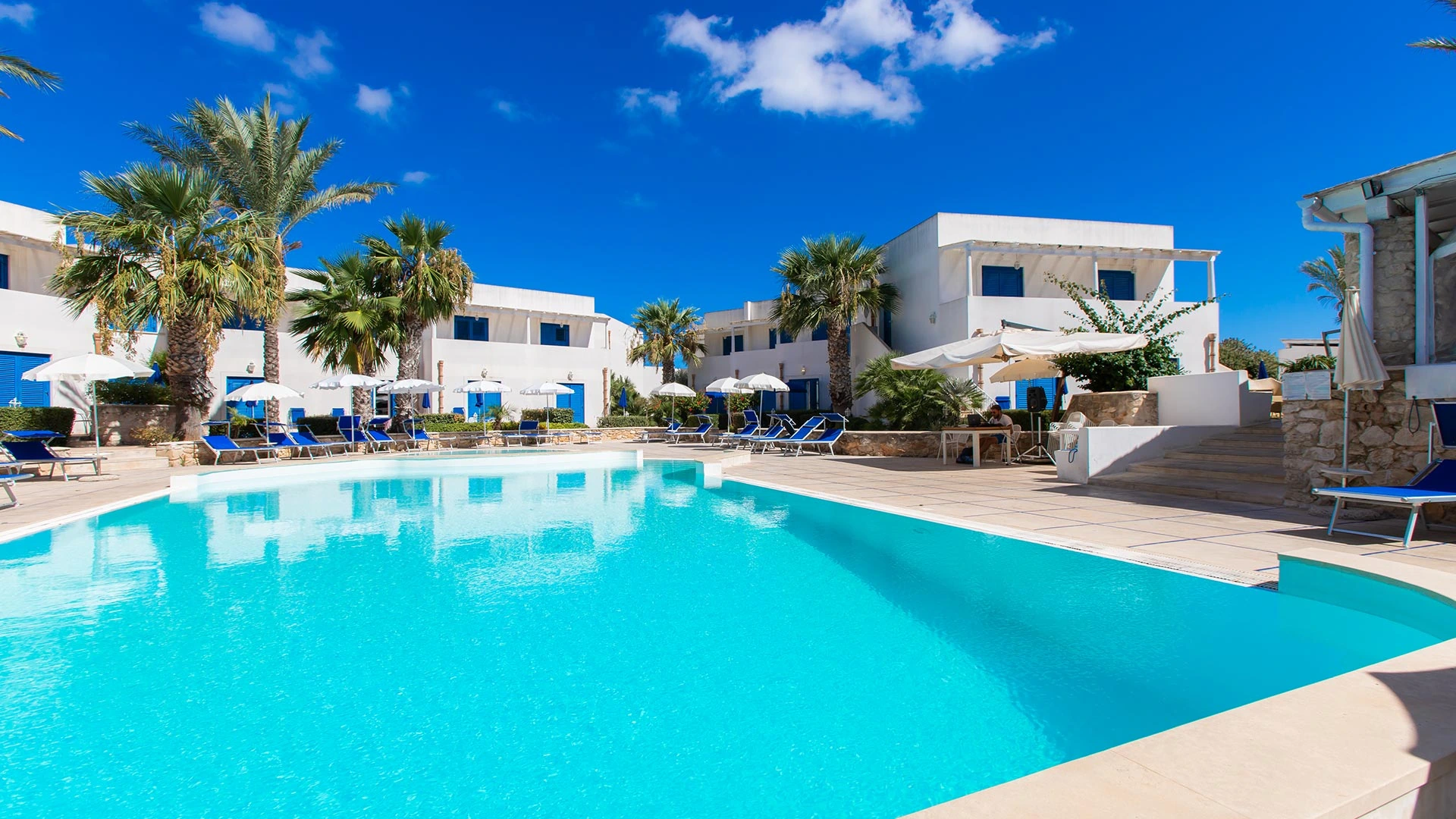 Piscina di Cala La Luna con palme e facciate bianche