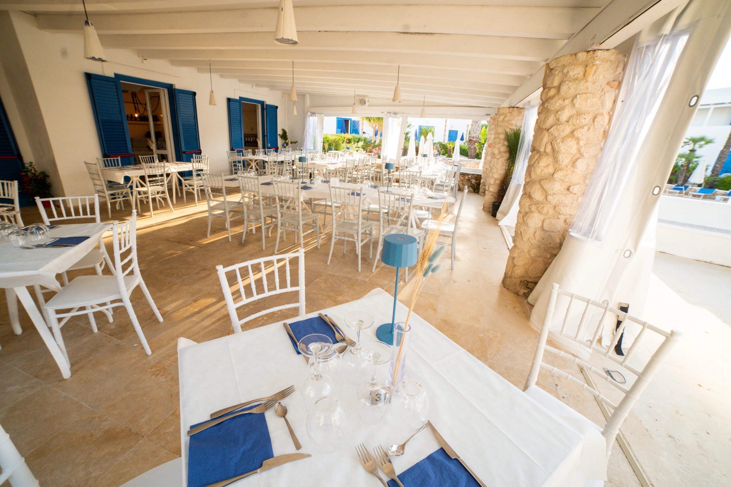 Sala del ristorante Poseidon con tavoli apparecchiati e sedie bianche