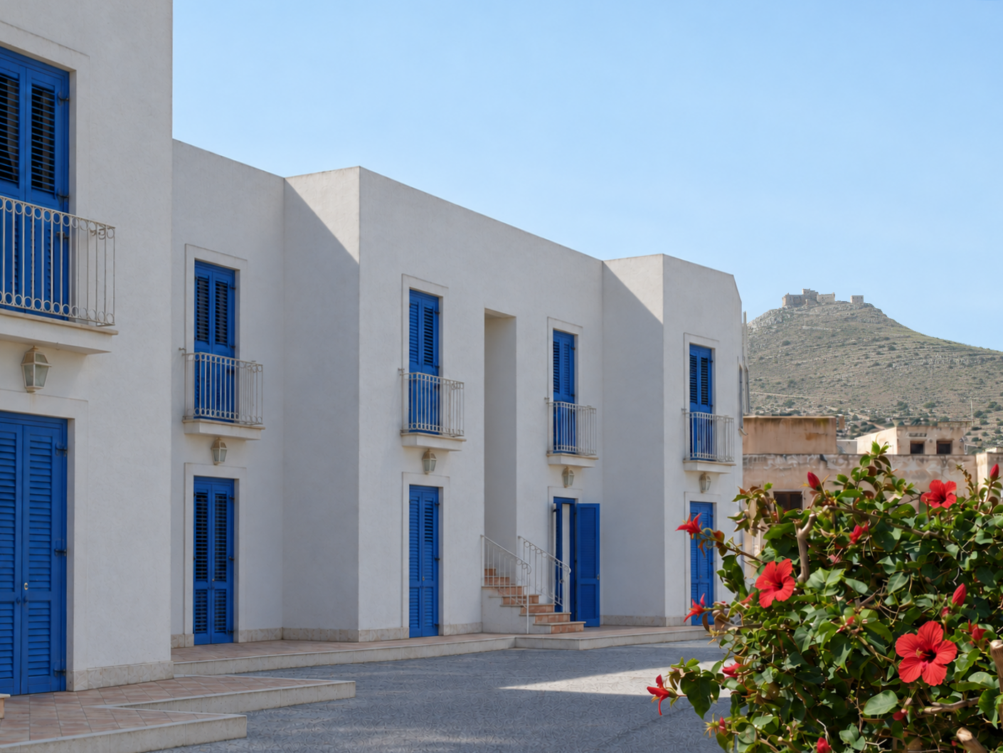 Façades blanches et volets bleus de Cala La Luna, avec la colline en arrière-plan